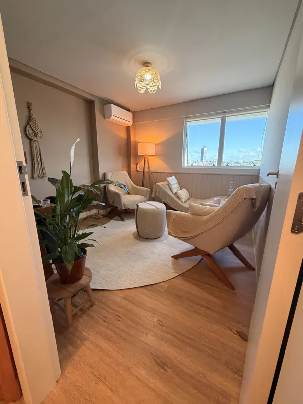 Sala de atendimento vista da porta, com planta, poltronas e divã