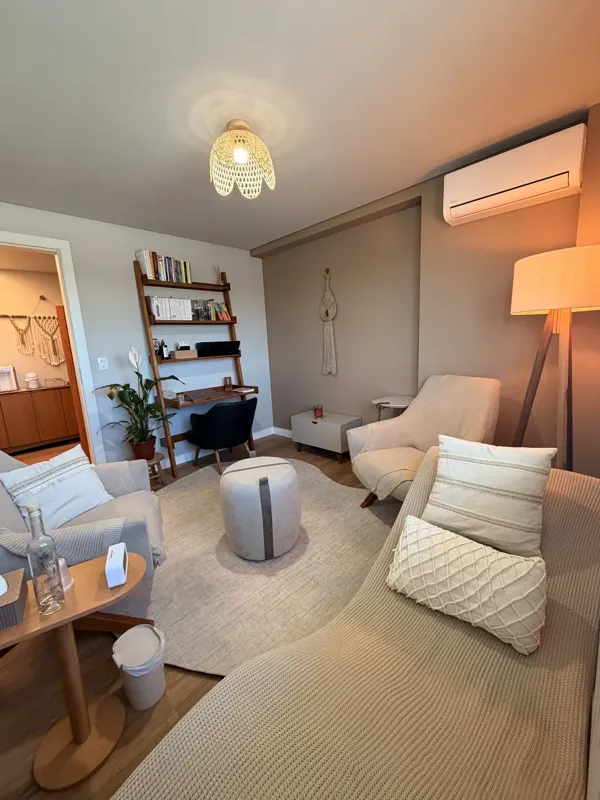 Sala de atendimento com estante de livros, poltronas e divã